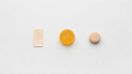 Flat lay of various supplement formats including a dissolving strip, a gummy, and a chewable tablet arranged neatly on a clean light surface  