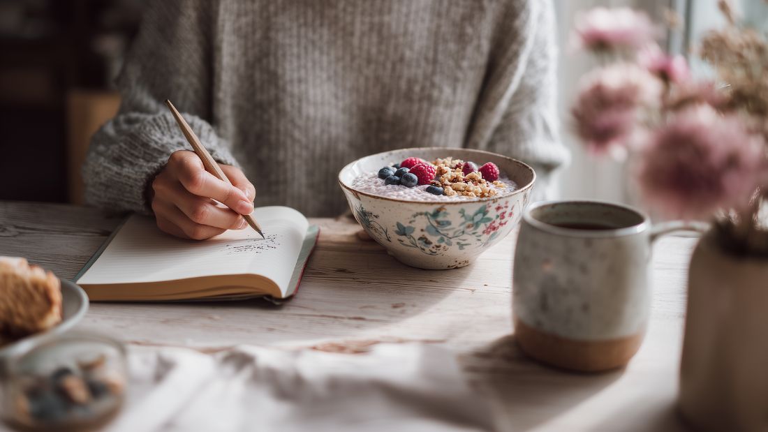 Person holding a warm mug in a cozy winter kitchen while preparing a fiber-rich snack