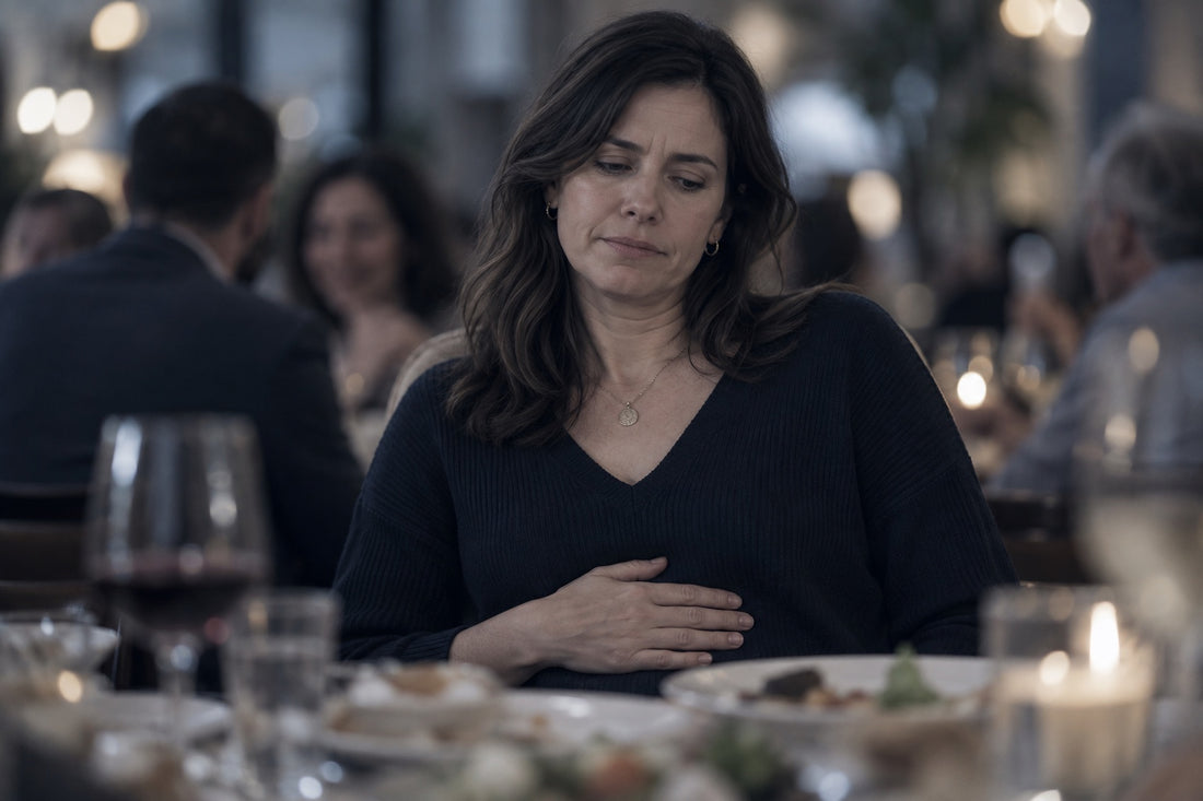 Woman at a restaurant table with her hand on her stomach