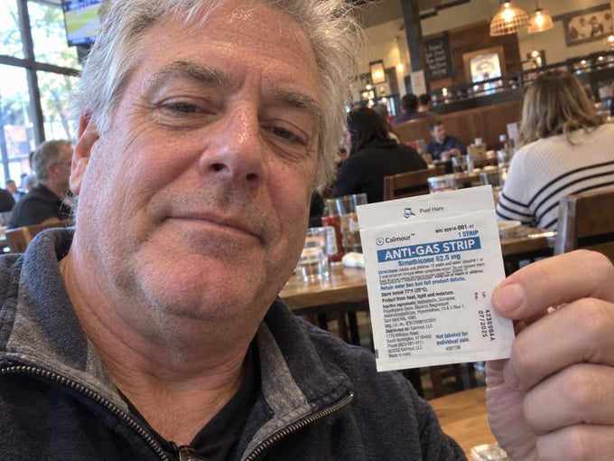 A Calmour customer holding an individually sealed anti-gas strip at a restaurant